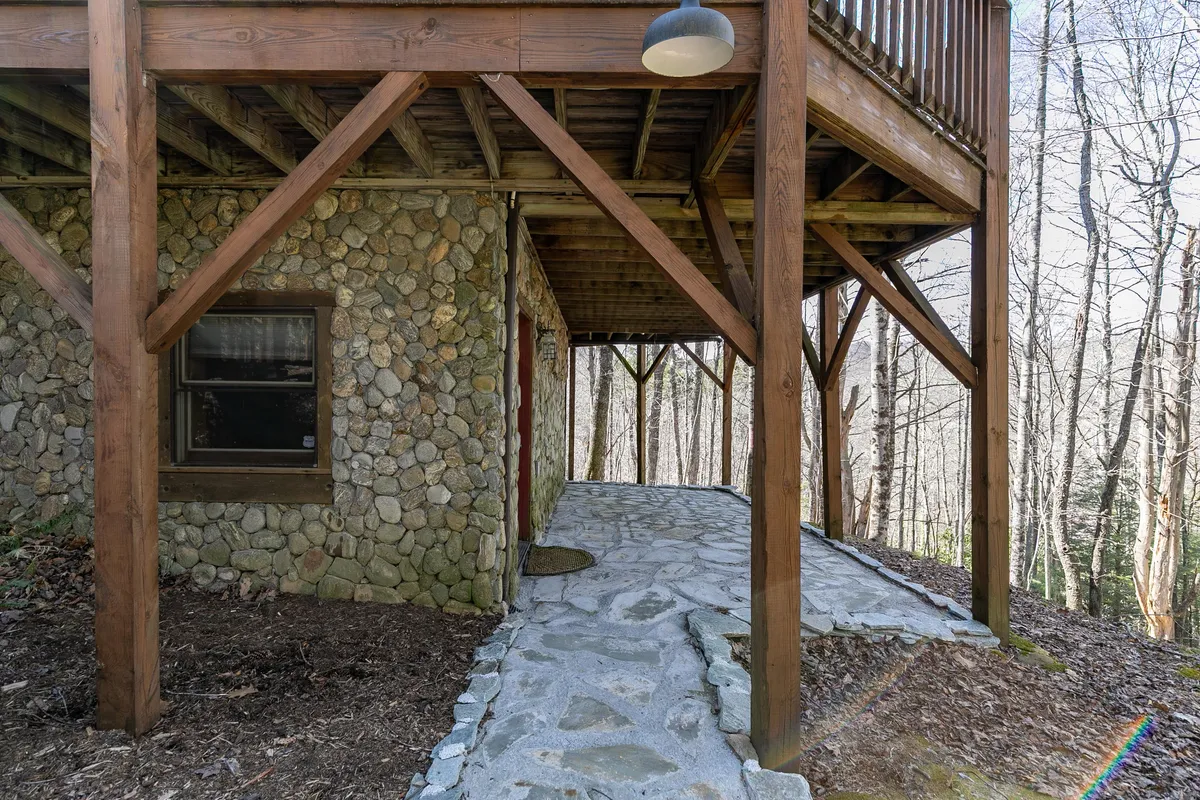 A tranquil view of the cottage’s stone exterior and wooden beams, with a pathway leading into the surrounding woods. This image emphasizes the natural setting and the adventure possibilities right outside the door.