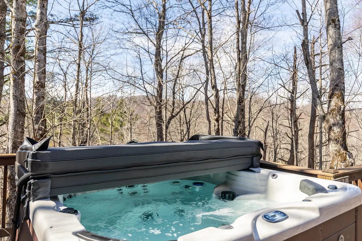 This image features an inviting hot tub on a wooden deck, surrounded by lush trees. The deck provides a serene outdoor space for relaxing after a day of adventure, with nature views in every direction.